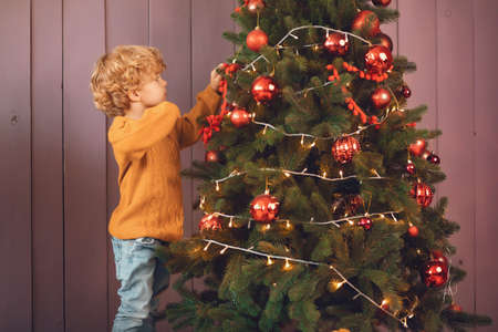 Little boy near christmas tree in a brown sweater