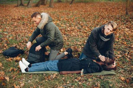 Two boys in a autumn park help a african girlの写真素材