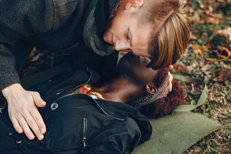 Man in a autumn park help a african girlの写真素材