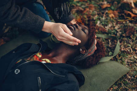 Man in a autumn park help a african girlの写真素材