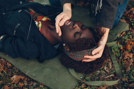 Man in a autumn park help a african girl