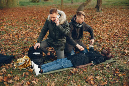 Two boys in a autumn park help a african girlの写真素材