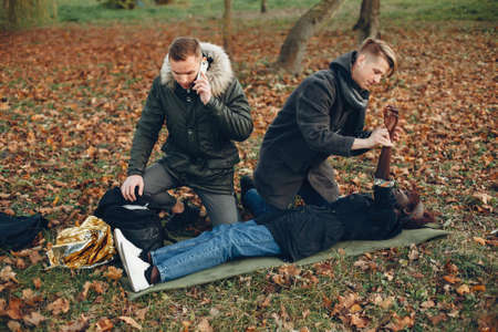Two boys in a autumn park help a african girlの写真素材