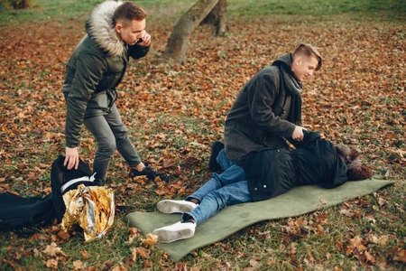 Two boys in a autumn park help a african girlの写真素材