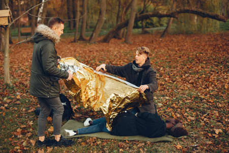 Two boys in a autumn park help a african girlの写真素材