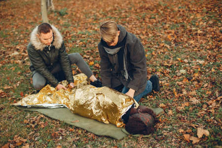 Two boys in a autumn park help a african girl