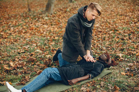 Man in a autumn park help african girlの写真素材