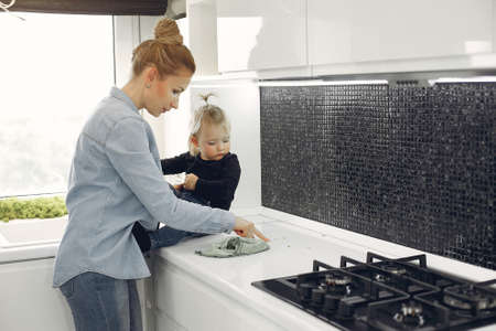 Mom and daughter clean up in the kitchenの写真素材