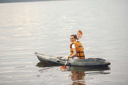 Woman paddling on a lake in a kayakの写真素材