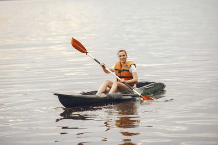Woman paddling on a lake in a kayakの写真素材