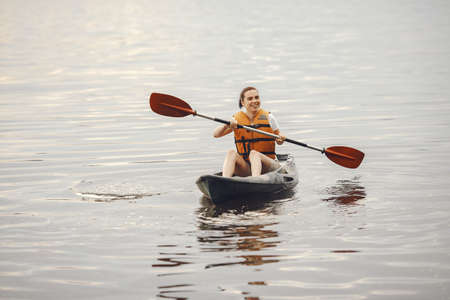 Woman paddling on a lake in a kayakの写真素材