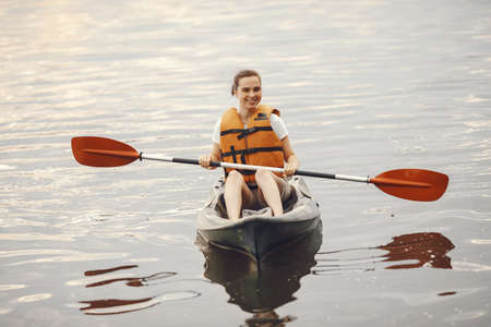 Woman paddling on a lake in a kayakの写真素材