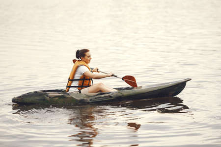 Woman paddling on a lake in a kayakの写真素材