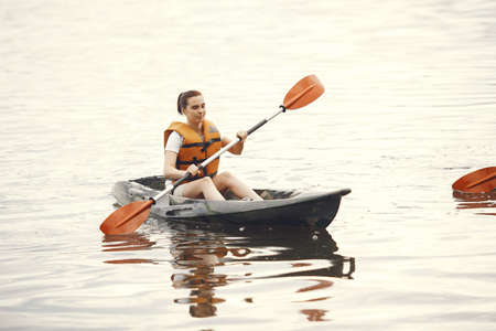 Woman paddling on a lake in a kayakの写真素材