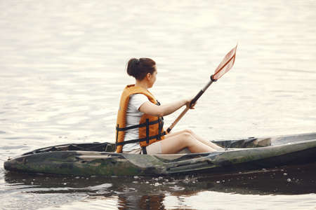 Woman paddling on a lake in a kayakの写真素材