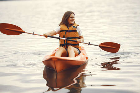 Woman paddling on a lake in a kayakの写真素材