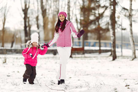Mother and child in winter clothes play in winter parkの写真素材