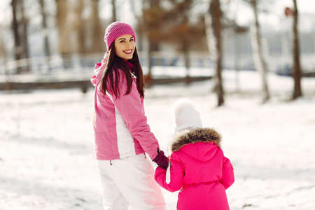 Mother and child in winter clothes play in winter parkの写真素材