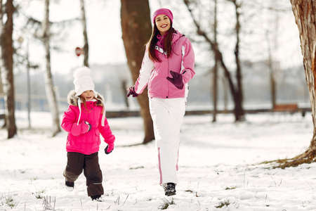 Mother and child in winter clothes play in winter parkの写真素材