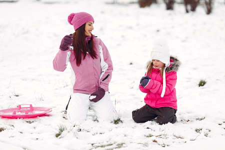 Mother and child in winter clothes play in winter parkの写真素材