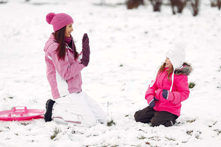 Mother and child in winter clothes play in winter parkの写真素材
