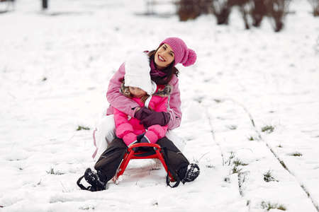 Mother and child in winter clothes play in winter park