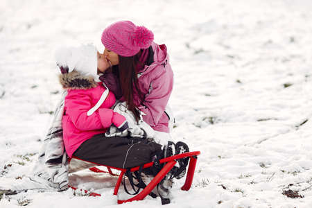 Mother and child in winter clothes play in winter park
