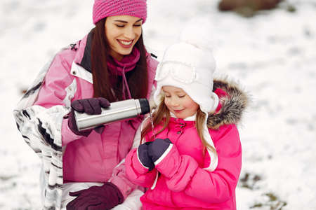 Mother and child in winter clothes play in winter parkの写真素材