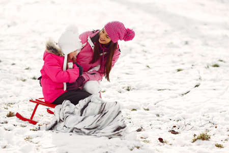 Mother and child in winter clothes play in winter parkの写真素材