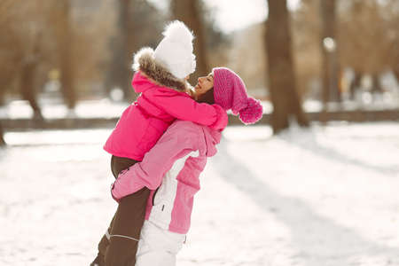 Mother and child in winter clothes play in winter parkの写真素材
