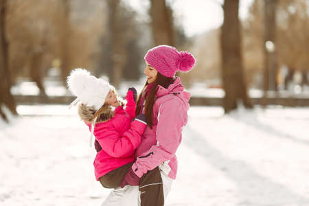 Mother and child in winter clothes play in winter parkの写真素材