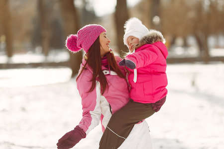 Mother and child in winter clothes play in winter parkの写真素材