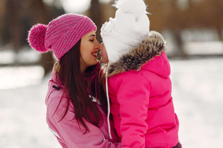 Mother and child in winter clothes play in winter parkの写真素材