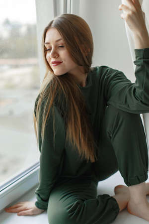 Woman sitting on a windowsill at homeの写真素材