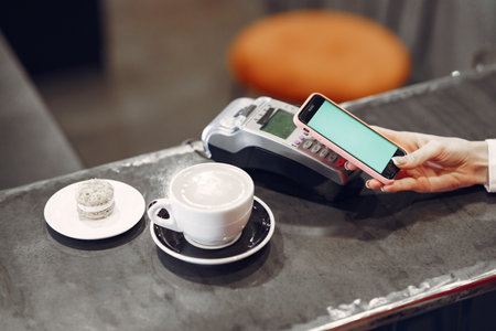 Girl paying for her latte with a smartphone by contactless PAY PASS technologyの写真素材