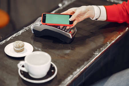 Girl paying for her latte with a smartphone by contactless PAY PASS technologyの写真素材