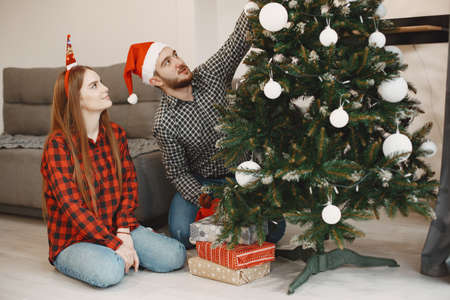 Cute couple sitting at home near christmas treeの写真素材