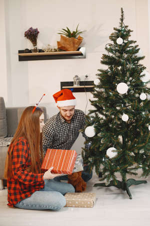 Cute couple sitting at home near christmas treeの写真素材