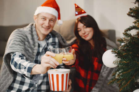 Cute couple sitting at home near christmas treeの写真素材