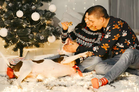 Cute couple sitting at home near christmas treeの写真素材