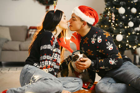 Cute couple sitting at home near christmas treeの写真素材