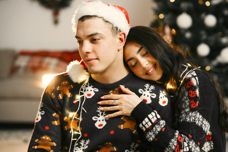 Cute couple sitting at home near christmas treeの写真素材
