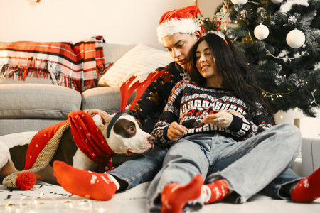 Cute couple sitting at home near christmas treeの写真素材
