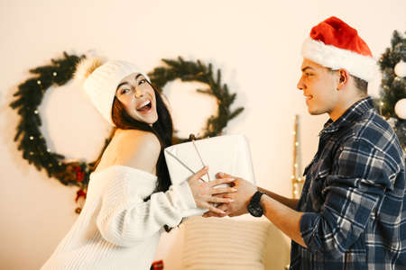 Cute couple sitting at home near christmas treeの写真素材