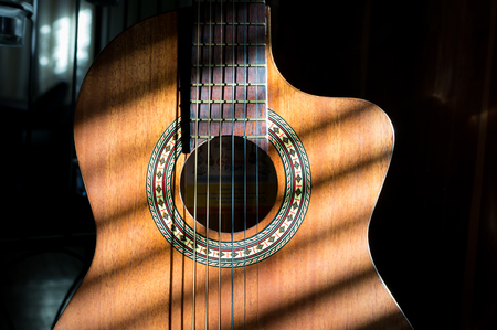 Close up of classical guitar with striped shadows across the body and neck