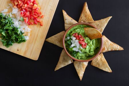 Traditional mexican sauce guacamole in clay bowl and nachos on the background of a slate boardの写真素材