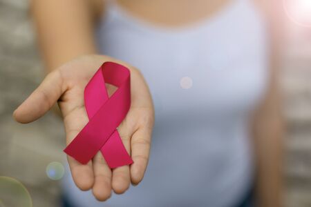 Woman holding pink ribbon on light background, closeup. Breast cancer awareness conceptの写真素材