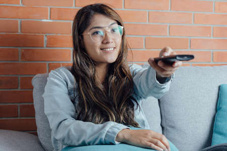 Mexican woman points with the television control excited points her finger at the screenの写真素材