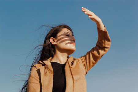 Woman covers herself from the sun with her hand. fashion