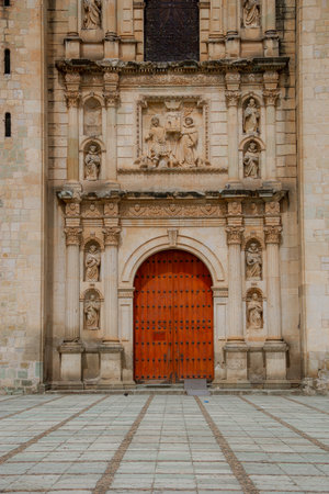 Symmetrical close-up of the main entrance of a colonial church in Mexico, highlighting the baroque stone carvings and wooden door details.の写真素材